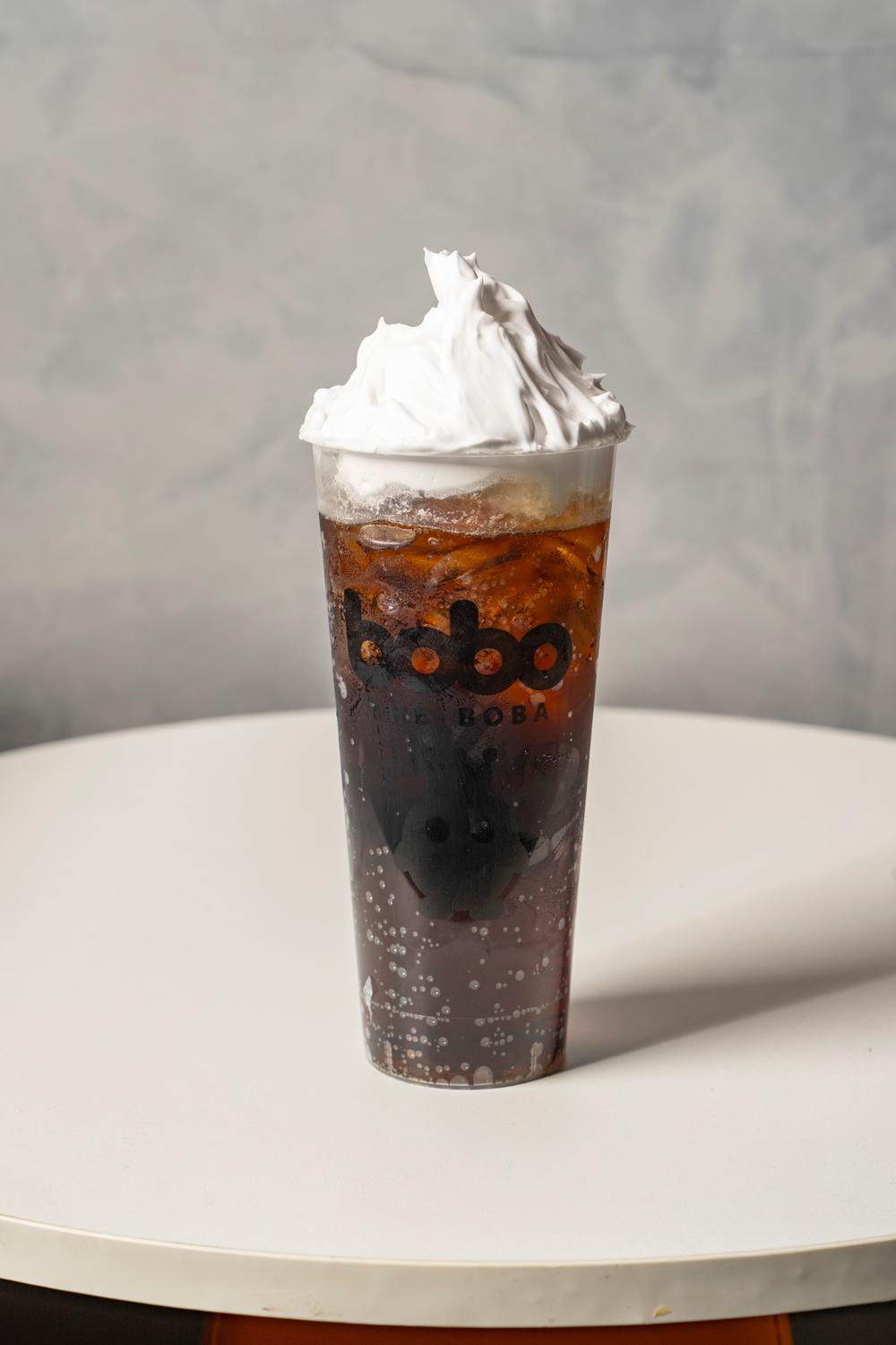 Iced cola drink topped with whipped cream