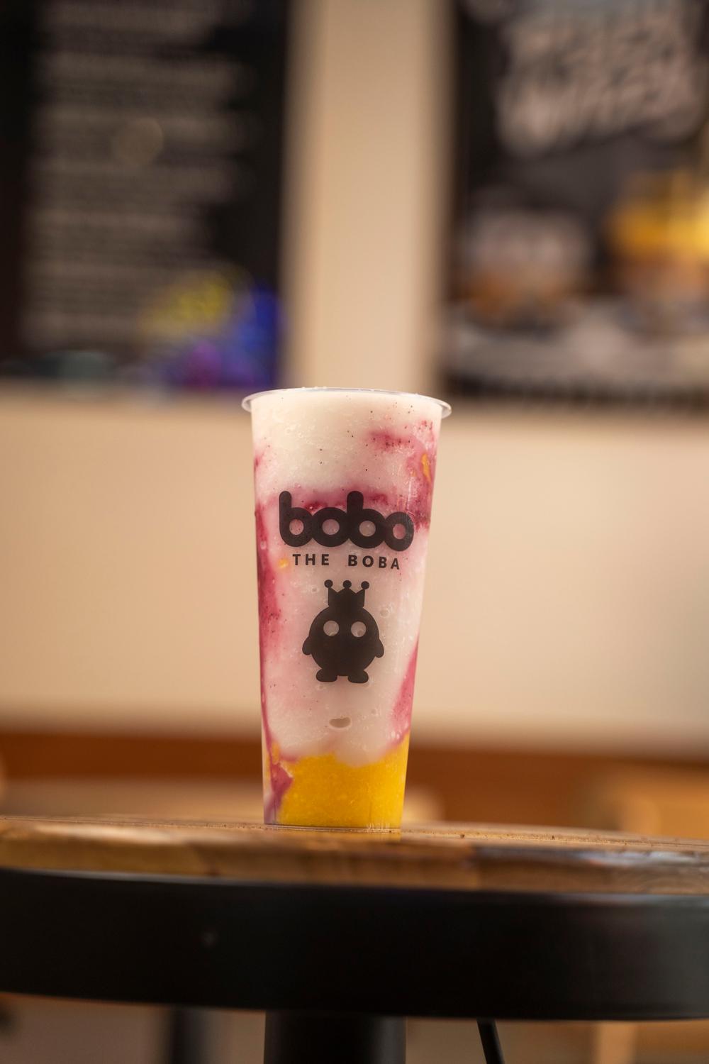 Mango berry smoothie in front of the shop menu